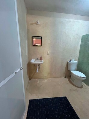 A small bathroom with a sink, toilet, and a mirror. - Your peaceful and cozy space in Zicatela (Brisas de Zicatela)