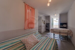 Ein Zimmer mit einem Bett, einem Tisch und Blick durch eine offene Tür.
