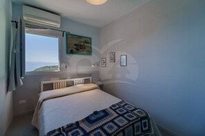 A bedroom with a bed, a radiator, a window with a view, and wall art.
