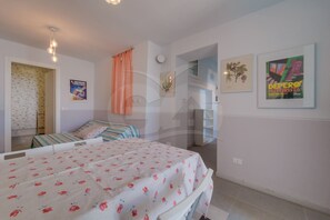 Ein Schlafzimmer mit Bett, einem Fenster mit Vorhängen, einer Wandleuchte und einem Poster.