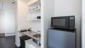 Ett modernt kök med inbyggd mikrovågsugn, diskho i rostfritt stål och vita köksluckor.