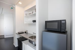 A modern kitchen with a built-in microwave, stainless steel sink, and white cabinetry. - JAPAVISTA R4 (ROPPONGI, MINATO CITY)