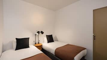 Una habitación de hotel con dos camas, una mesita de noche con lámparas y una puerta.