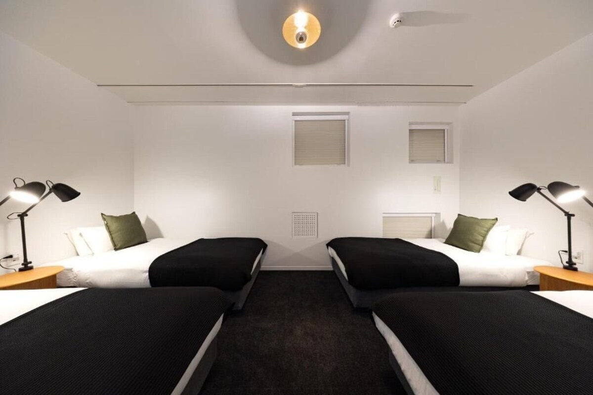 A hotel room with two beds, a ceiling light, and a window.