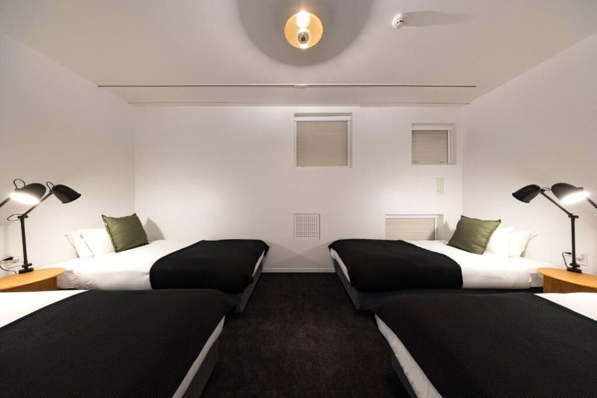 Une chambre d’hôtel avec deux lits, un luminaire au plafond et une fenêtre.
