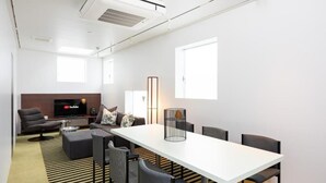 Ett modernt vardagsrum med ett vitt bord, svarta stolar, en soffa och en platt-TV.