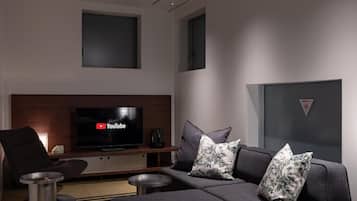 Una sala moderna con televisor de pantalla plana, sofá gris y cojines decorativos.