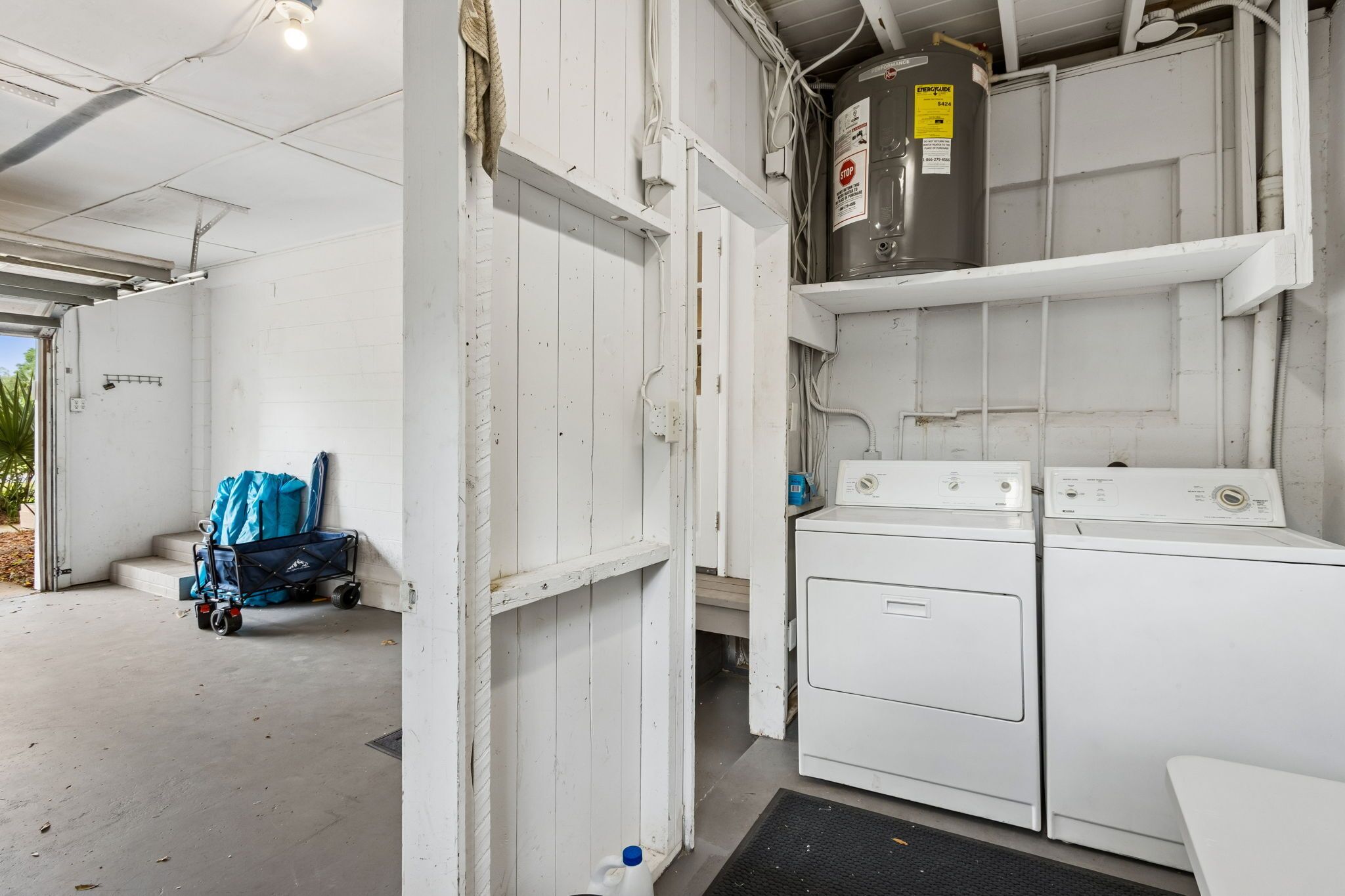 A laundry area with a washing machine, dryer, and a cart with bags.