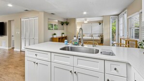 A modern kitchen with white cabinets, a stainless steel sink, and a ceiling fan. - Blake's Place: Quiet 3bd/2ba home with Mega Hot Tub + Cold Plunge (Jacksonville Beach)
