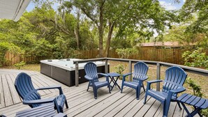 A deck with Adirondack chairs, a hot tub, and a wooden fence. - Blake's Place: Quiet 3bd/2ba home with Mega Hot Tub + Cold Plunge (Jacksonville Beach)
