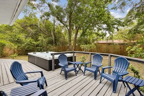 Eine Terrasse mit Adirondack-Stühlen, einem Whirlpool und einem Holzzaun.