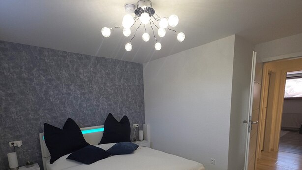 A bedroom with a bed, bedside tables, a ceiling light fixture, and a door. - "Auszeit" Vacation Rental in Irslingen  (Dietingen)