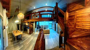 Ein geräumiges Loft mit einer Holztreppe, einem Essbereich und einer Küche.