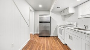 A compact kitchen with a stainless steel refrigerator, a built-in oven, and white cabinetry.