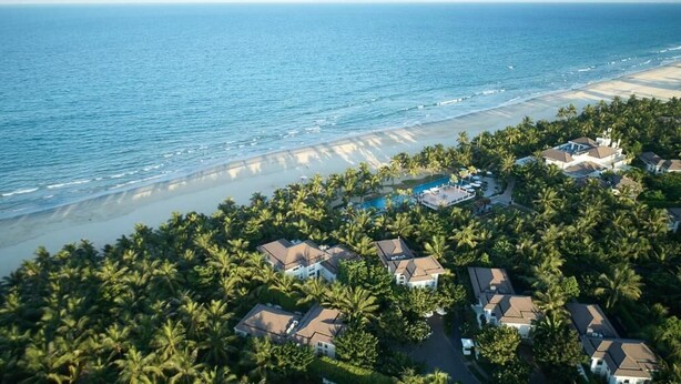 An aerial view of a coastal residential area with houses, a swimming pool, and a beach. - Premier Villa Da Nang by DDH (Da Nang)