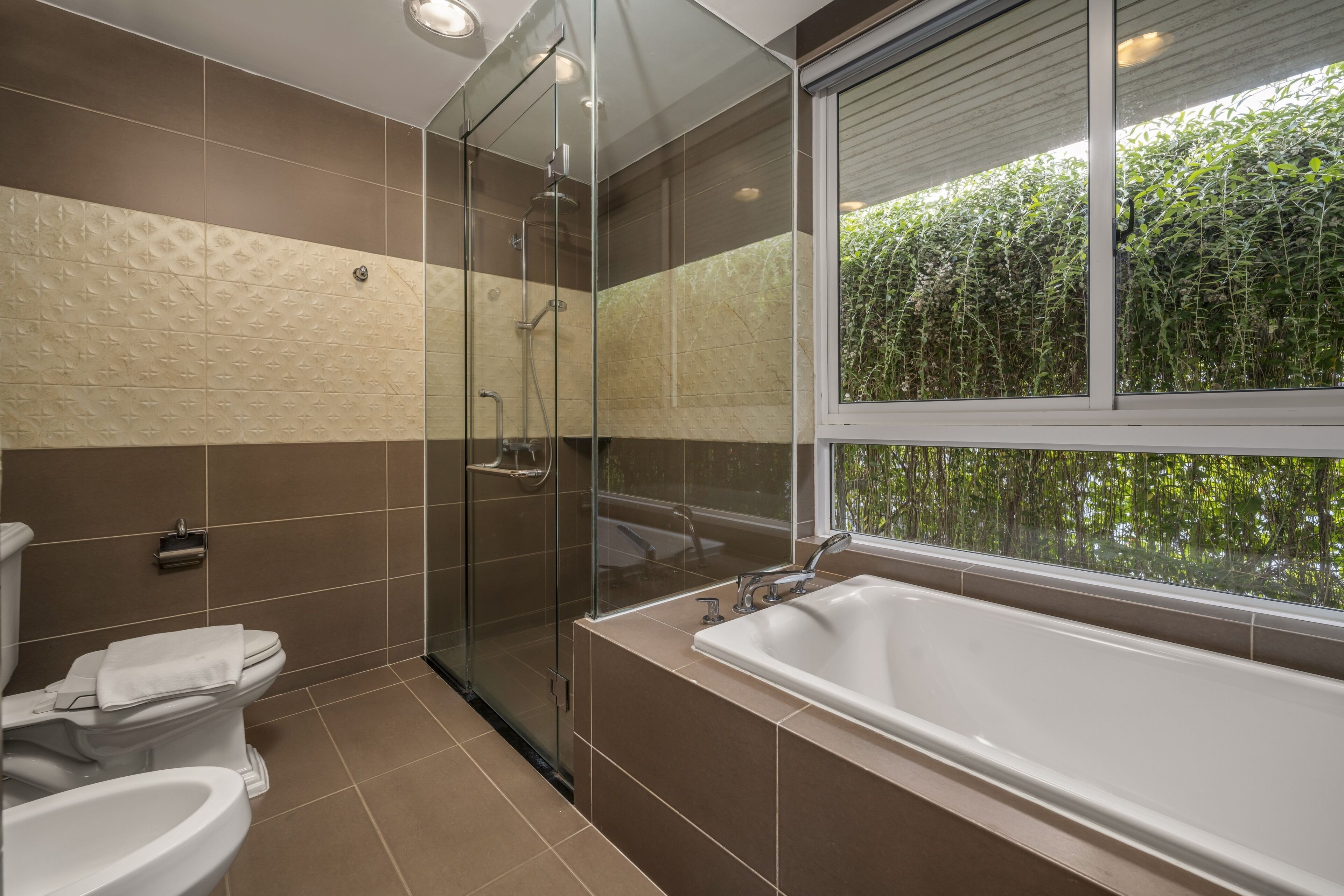 A modern bathroom with a glass-enclosed shower, a large bathtub, and a toilet.