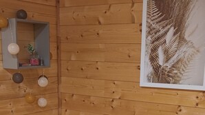 Una stanza in legno con un letto, uno scaffale con oggetti decorativi e un quadro appeso al muro.