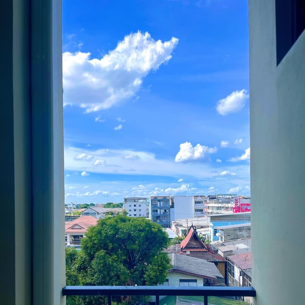 A view through a window of a cityscape with buildings and a tree. - RESET at DMK (Bangkok)