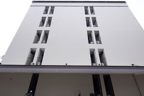 Un edificio de varios pisos con balcones, ventanas grandes y techo plano.