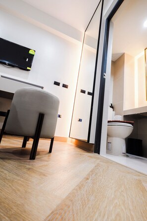 A modern bathroom with a toilet, a mirror, and a chair.