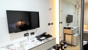 Un baño moderno con espejo, lavamanos, inodoro y un refrigerador pequeño.