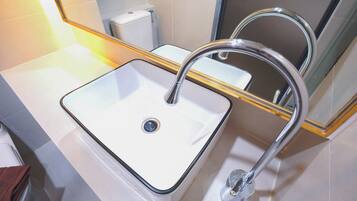 A bathroom with a white sink, chrome faucet, and a mirror with a gold frame.
