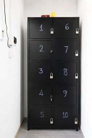A black storage cabinet with numbered compartments, each secured with a padlock.