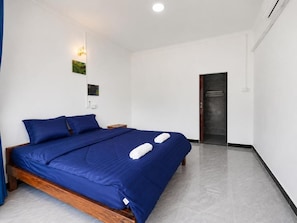 Une chambre à coucher avec un lit en bois, des murs blancs, une porte et une petite table de chevet.