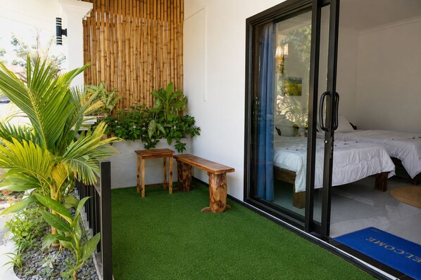 A balcony with artificial grass, wooden furniture, and potted plants. - David's Hostel & Restaurant (Koh Rong)