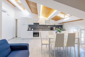 Eine moderne Küche mit weißen Schränken, einer schwarzen Rückwand und einer Holzbalkendecke.