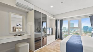 A modern hotel room with a city view, a large bed, a desk, and a wardrobe. - Magnolia by Kozystay - Kebon Jeruk (Jakarta Selatan)
