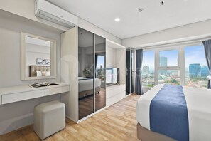 A modern hotel room with a city view, a large bed, a desk, and a wardrobe. - Magnolia by Kozystay - Kebon Jeruk (Jakarta Selatan)