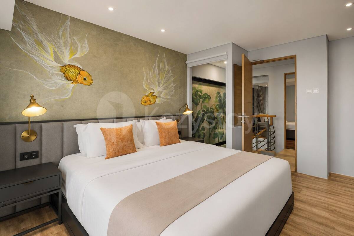 Una habitación de hotel moderna con una cama grande, dos lámparas de noche, una mesita de noche, un mural en la pared y vistas de una escalera.