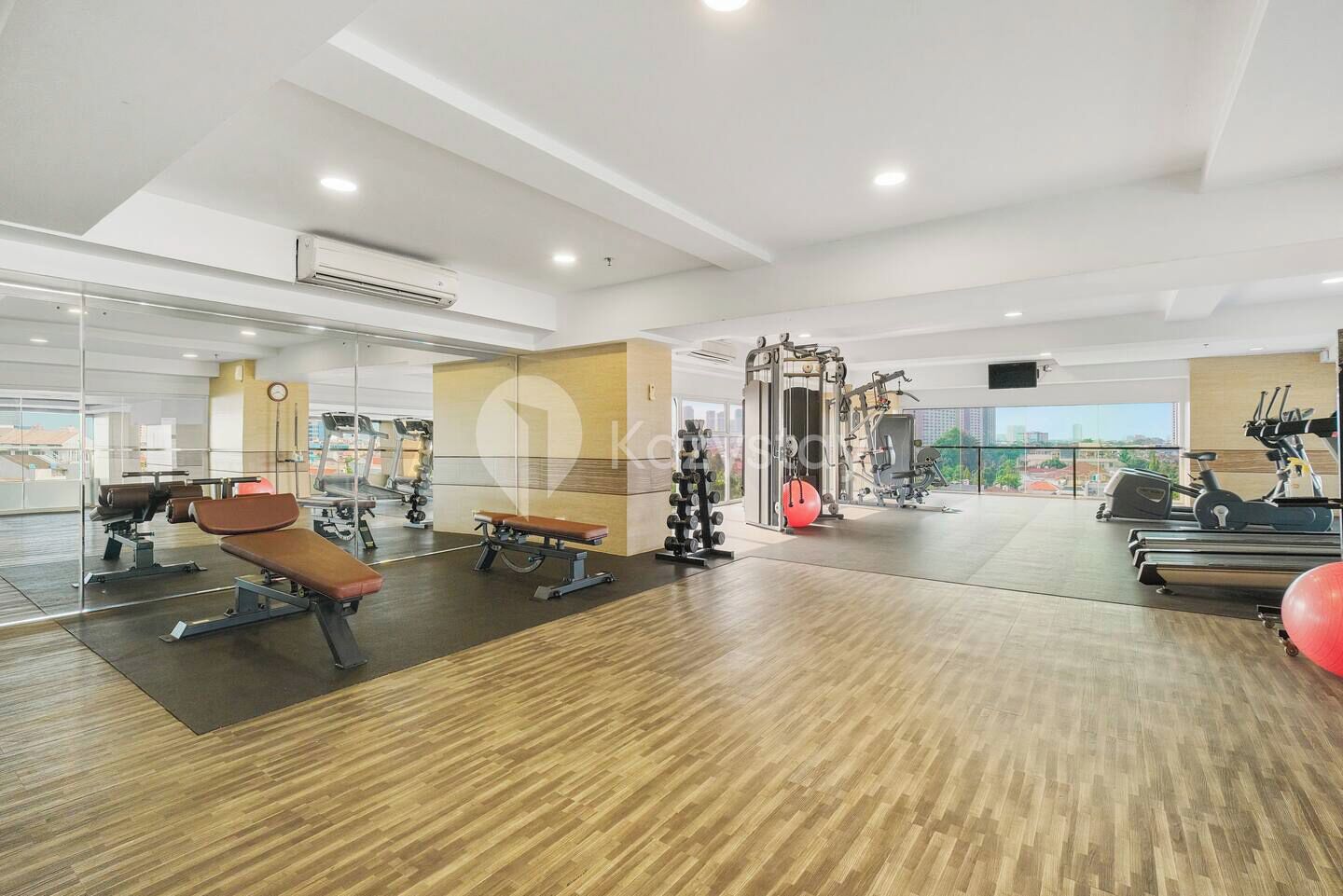 A modern gym with cardio machines, weightlifting equipment, and a large mirror.