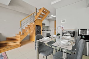 A modern kitchen with a wooden staircase, a dining table set for four, and a kitchen island.