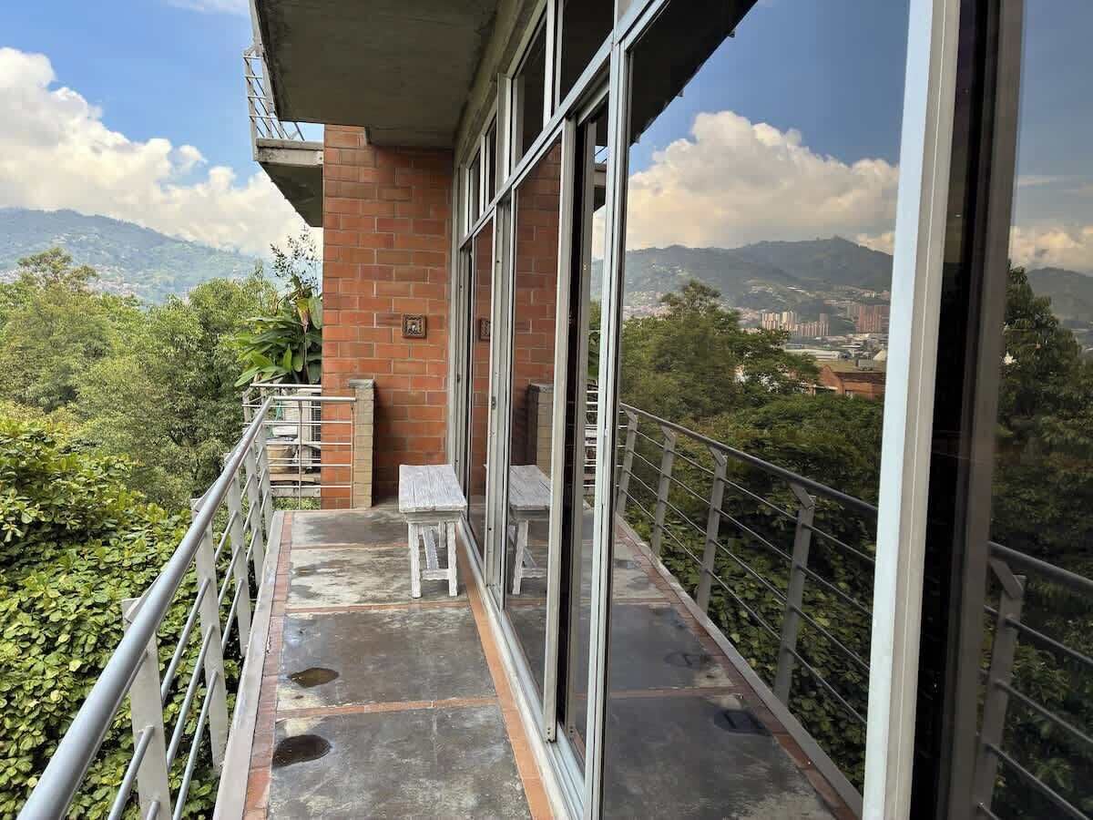 Un balcon avec vue sur les montagnes, un mur en briques et une balustrade.