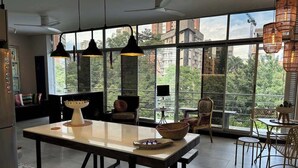 Een ruime eethoek met een grote tafel, stoelen en hanglampen.