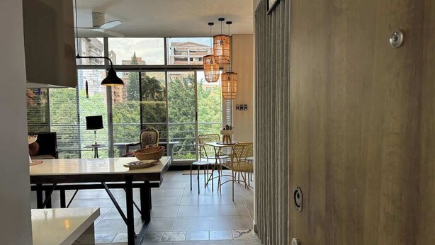 Een moderne keuken met een eethoek, grote ramen en uitzicht op groen.