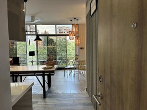A modern kitchen with a dining area, large windows, and a view of greenery. - lEPl Cool 2 Bd Duplex in Poblado W/ Good Location (Medellín)