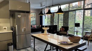 Een moderne keuken met een roestvrijstalen koelkast, een eettafel met een mand en hanglampen.