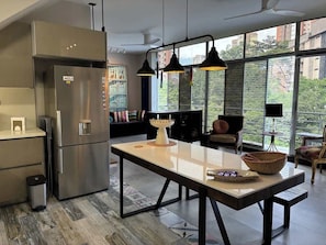 A modern kitchen with a stainless steel refrigerator, a dining table with a basket, and pendant lights. - lEPl Cool 2 Bd Duplex in Poblado W/ Good Location (Medellín)