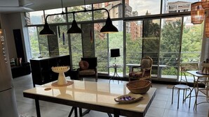 Een moderne keuken met een grote tafel, hanglampen en een stadszicht door grote ramen.