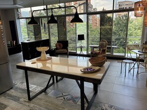 A modern kitchen with a large table, pendant lights, and a view of the city through large windows. - lEPl Cool 2 Bd Duplex in Poblado W/ Good Location (Medellín)