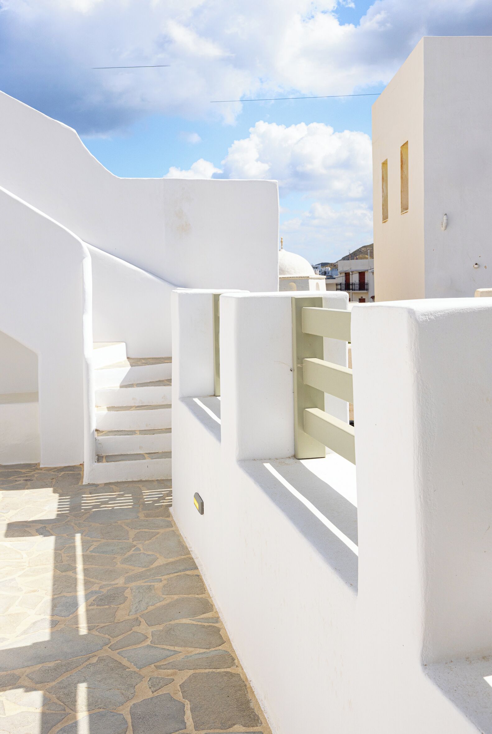 Un bâtiment blanc doté d’un sol en pierre et d’un escalier.