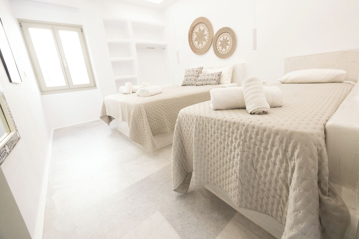 Quarto de hotel com duas camas, uma janela grande e um claraboia.
