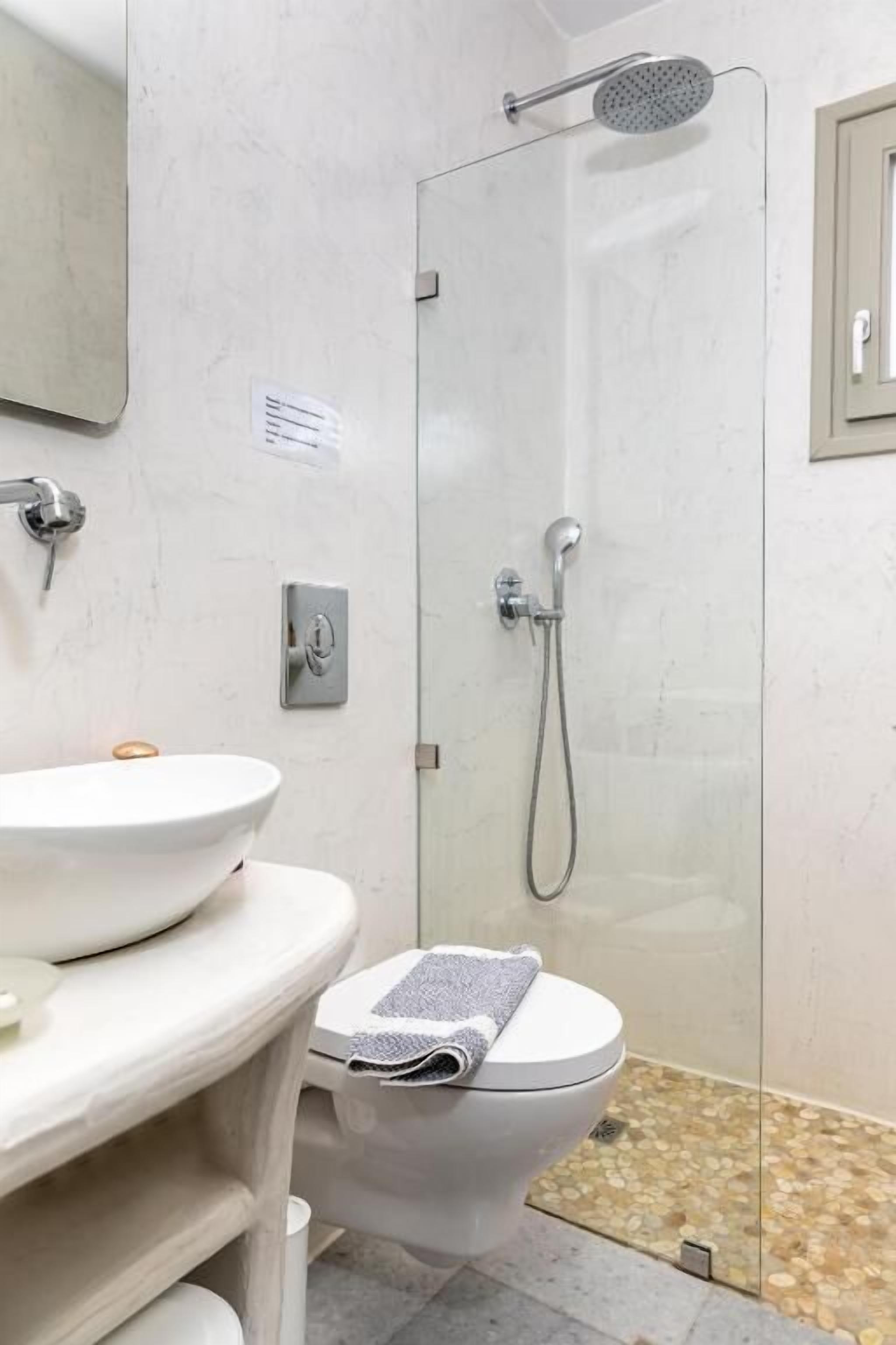 Un baño con inodoro, lavamanos, ducha y espejo.