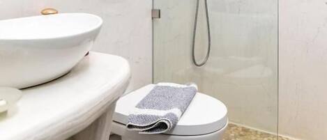 Un baño con inodoro, lavamanos, ducha y espejo.