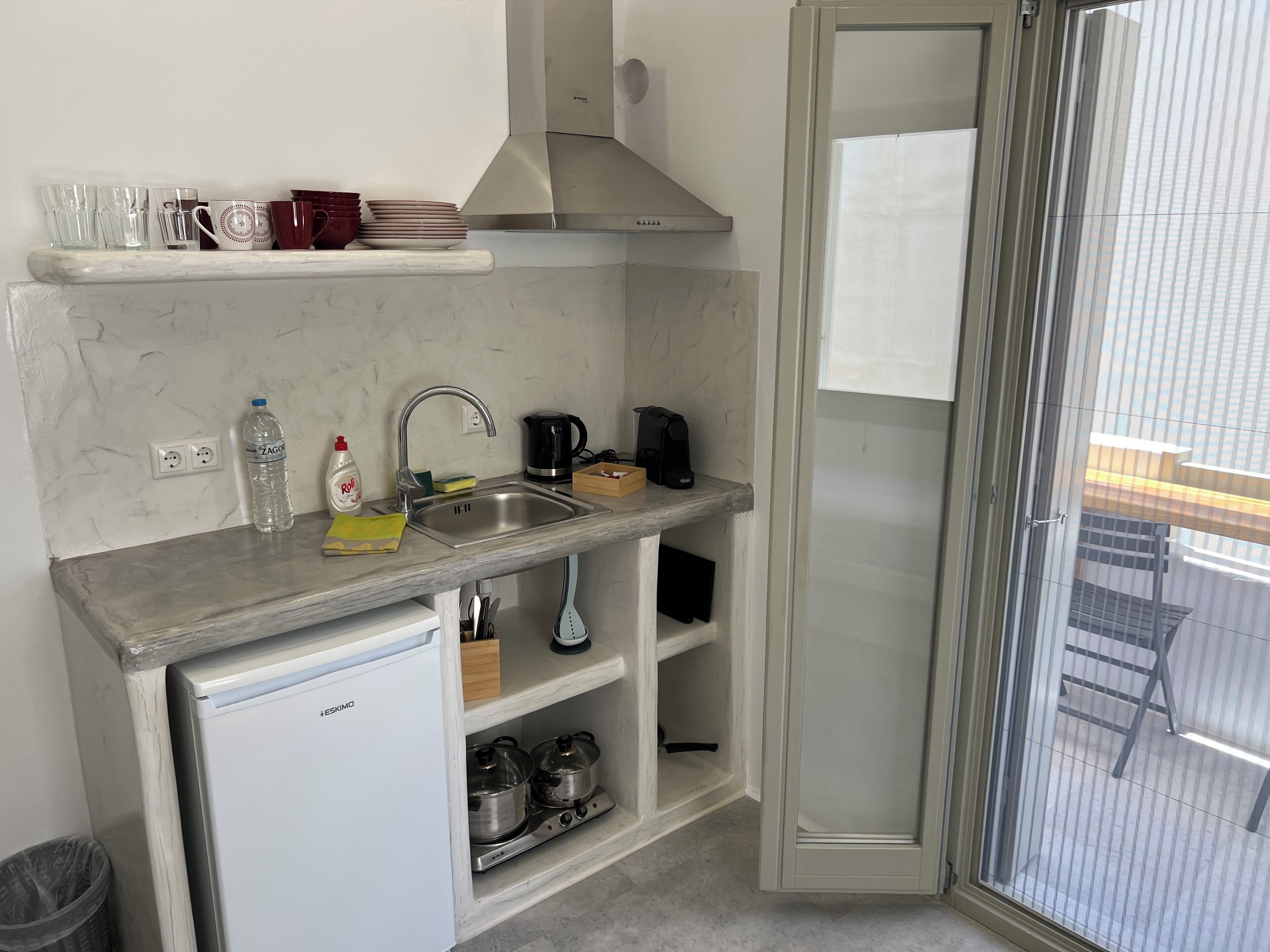A compact kitchen with a built-in refrigerator, a sink, a stove, and a coffee maker.