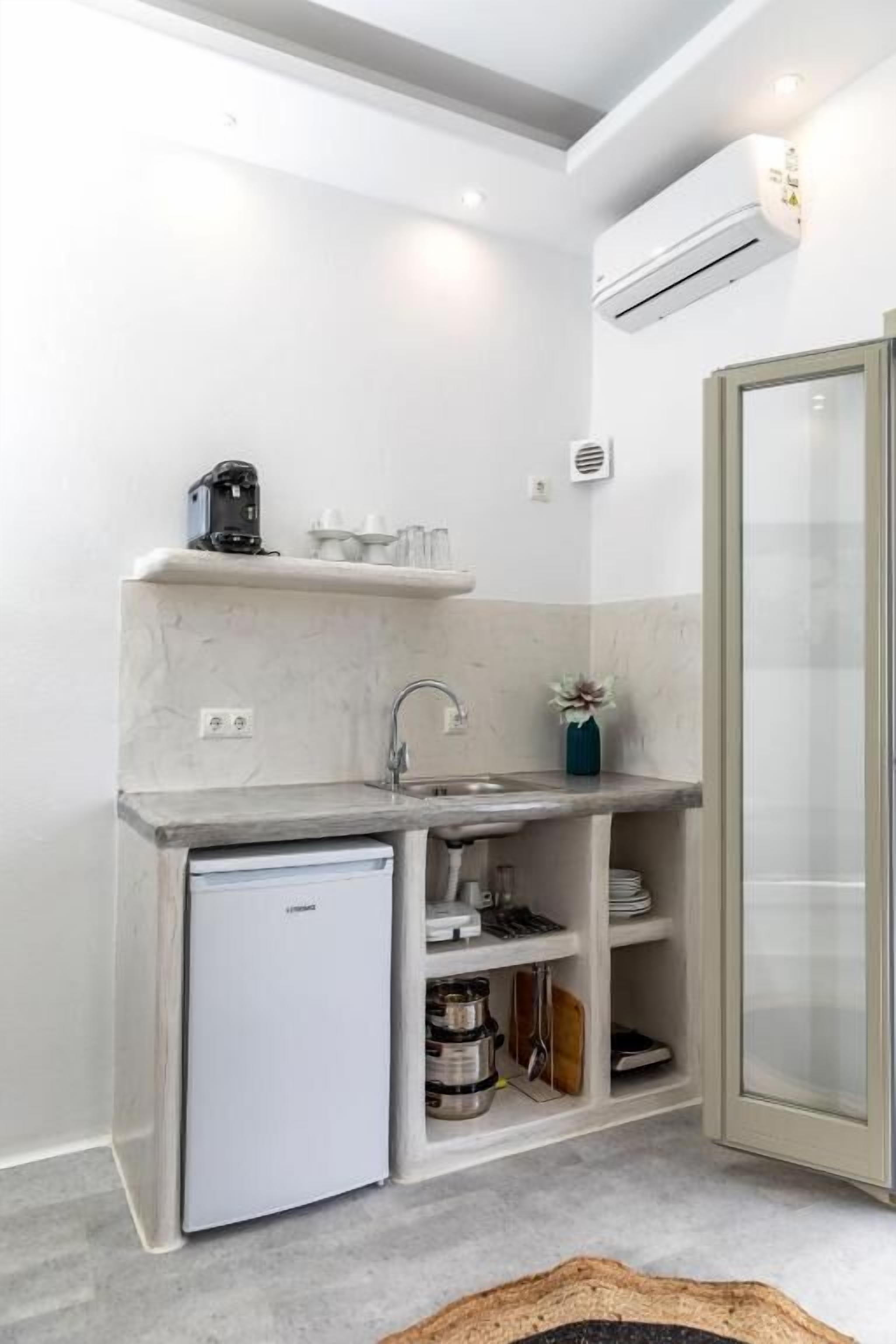 A compact kitchen with a built-in refrigerator, a sink, and a glass-enclosed shower.