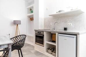 Una cocina compacta con horno integrado, un refrigerador pequeño y un lavamanos.
